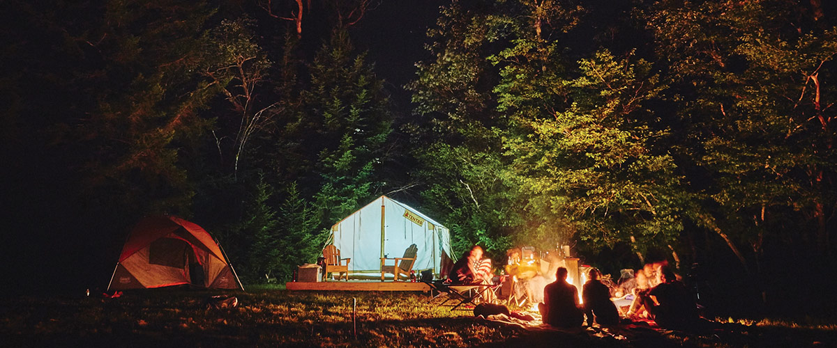 Night time shot of people around a campfire with a Tentrr tent